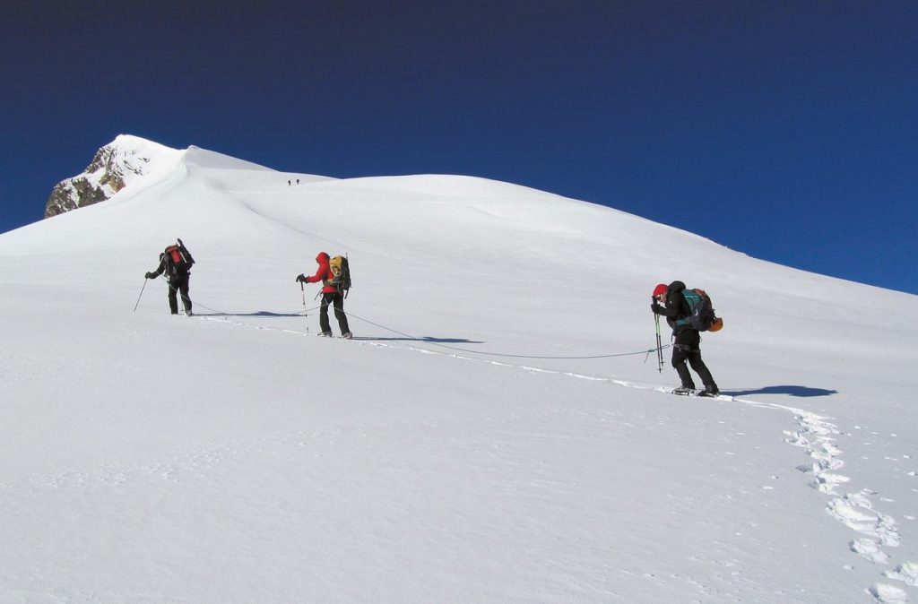 3 people climbing a snowy moutain 