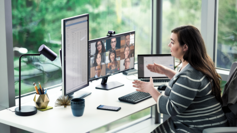 Employée d'entreprise travaillant au bureau avec plusieurs appareils et animant une conférence visioconférence Microsoft Teams.