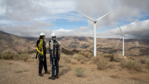 Homme et femme dans le désert devant un champ d'éoliennes - Transition énergétique